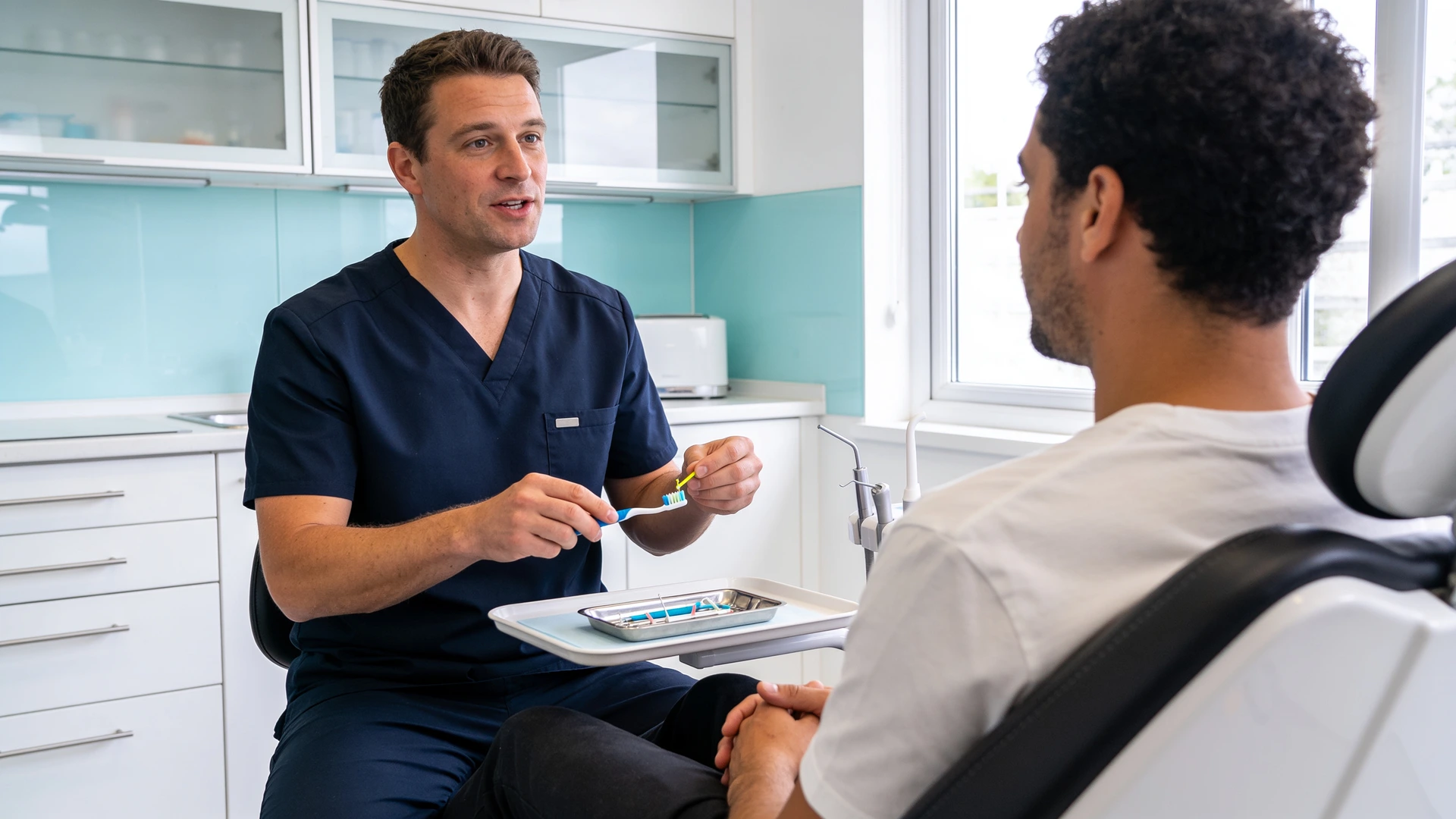 Zahnarzt erklärt einem Patienten Zahnbürste und Interdentalbürste in einer hellen Praxis